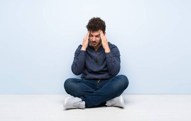 Young man sitting on the floor with headache - Photo, Image