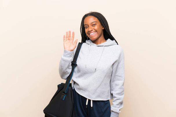 afrikanisch-amerikanische Sport Teenager Mädchen mit langen geflochtenen Haaren salutieren mit der Hand mit glücklichem Gesichtsausdruck - Foto, Bild