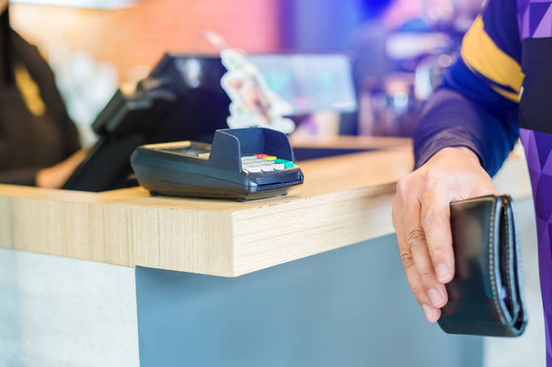 Enfoque selectivo al lector de tarjetas de crédito con cartera borrosa en la mano
 - Foto, imagen