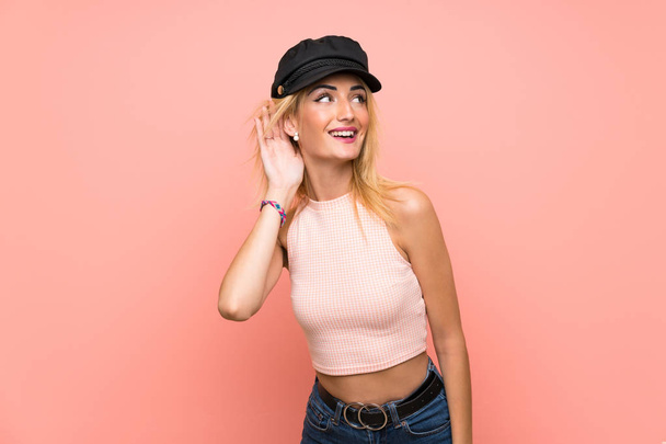Fiatal szőke nő kalapot hallgat valamit azáltal, hogy kezét a fül - Fotó, kép