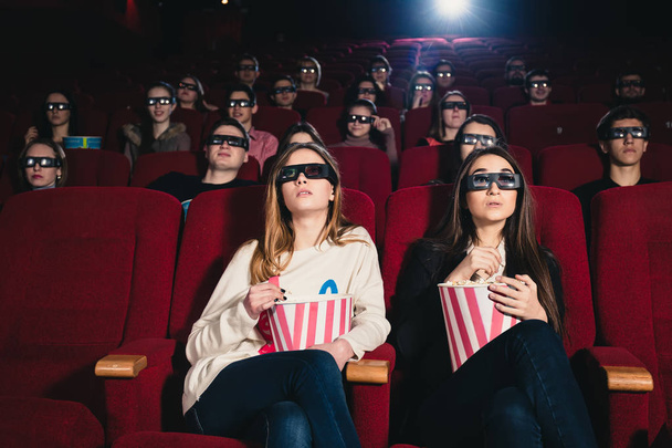 Girls friends in a cinema session eating popcorn - Zdjęcie, obraz