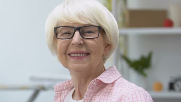 Smiling old woman in eyeglasses looking at camera, vision treatment, health care - Materiał filmowy, wideo