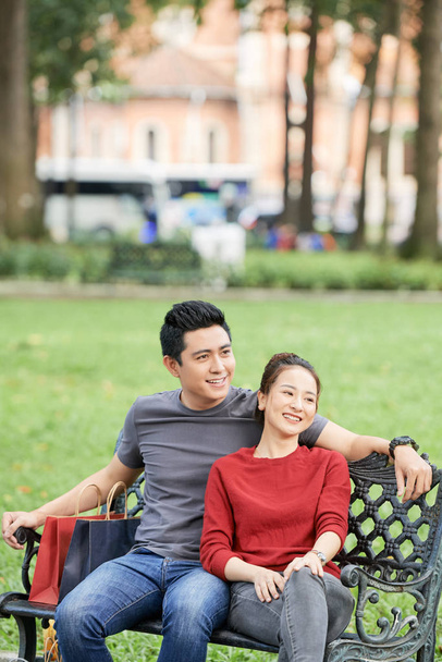 公園のベンチに座って恋に幸せな若いベトナムのカップル - 写真・画像