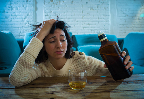Drunk alcoholic depressed woman drinking scotch whiskey spirits alone at home. Feeling hopeless, week and lonely. In People lifestyle, Depression, alcohol addiction, alcoholism and drug abuse concept. - 写真・画像