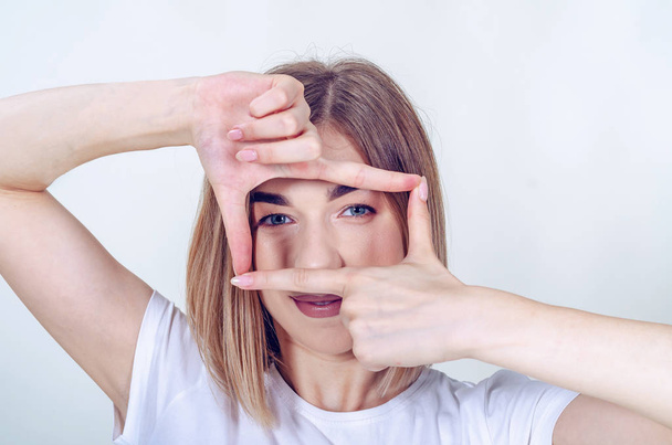 Girl made a rectangular frame of fingers opposite her eyes. - Photo, image
