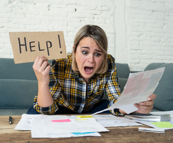 Lifestyle portrait of worried desperate young woman feeling stressed while working through finances at home showing Help sign. In single mother paying off debts and bills and financial problems. - 写真・画像