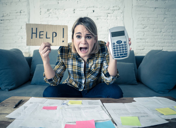 Worried young woman feeling stressed while accounting business and home finances. Desperate showing Help sign and calculator. In bad economic situation, paying debts, bills and financial problems. - Foto, Imagen