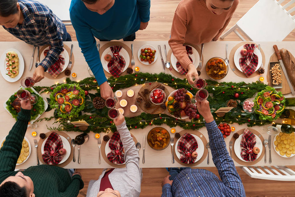 Nuoret clinking lasit yli joulun ruokapöytä
 - Valokuva, kuva
