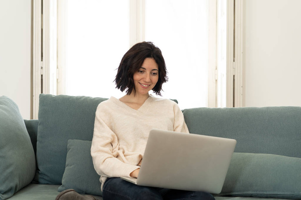 Lifestyle portrait of attractive relaxed woman using computer laptop, enjoying watching online movie, browsing social media and working or studying at home. In internet technology and network concept. - 写真・画像