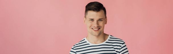 panoramic shot of smiling young man looking at camera isolated on pink - Photo, Image