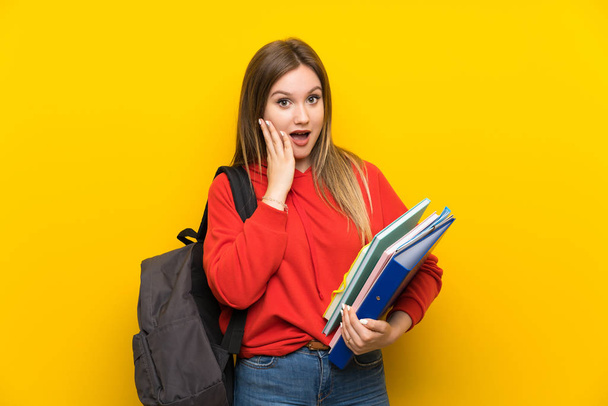 Adolescente estudiante sobre fondo amarillo con la expresión facial sorpresa
 - Foto, Imagen
