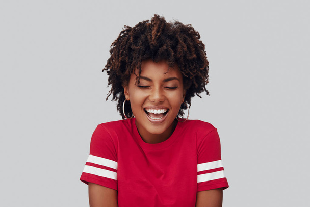  Attractive young African woman smiling while standing against grey background  - Φωτογραφία, εικόνα