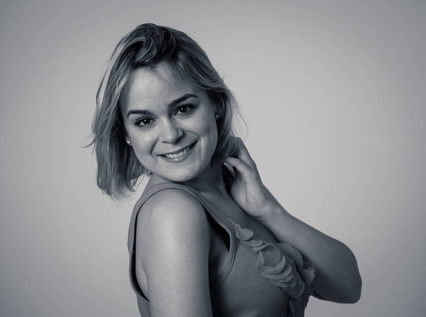 Black and white over the shoulder portrait of young pretty caucasian woman with blond hair smiling. Copy space. Feeling confident, relaxed posing and modeling. In lifestyle and beauty concept. - Foto, afbeelding