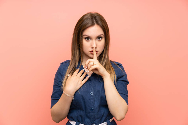 Adolescente chica sobre aislado rosa fondo mostrando un signo de silencio gesto poner dedo en la boca - Foto, Imagen