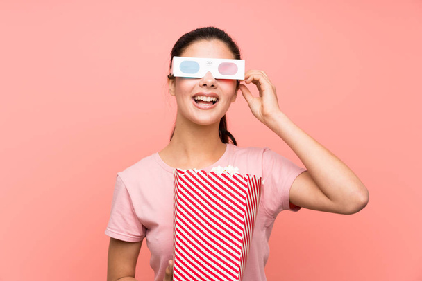 3Dメガネでポップコーンを食べる孤立したピンクの壁の上のティーンエイジャーの女の子 - 写真・画像