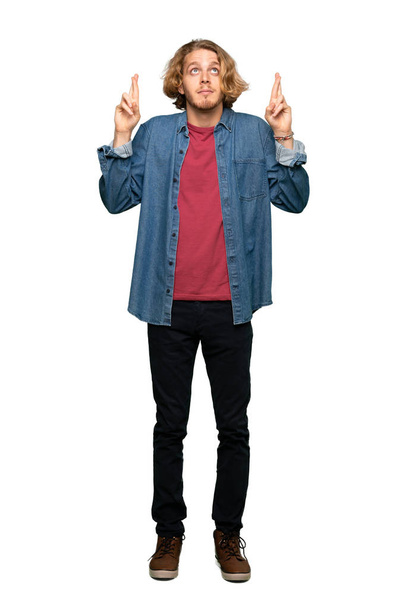 Full-length shot of Blonde man with fingers crossing and wishing the best over isolated white background - Photo, Image