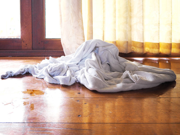 biały używany ręcznik na drewnianej brązowej podłodze w sypialni. - Zdjęcie, obraz