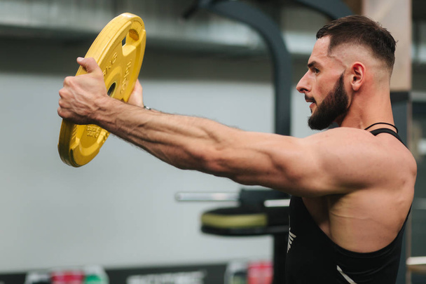 Bearden bodybuilder in the gym. Strong man in black t-shirt - Фото, изображение