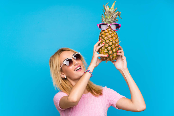 Mujer joven sosteniendo una piña con gafas de sol
 - Foto, Imagen