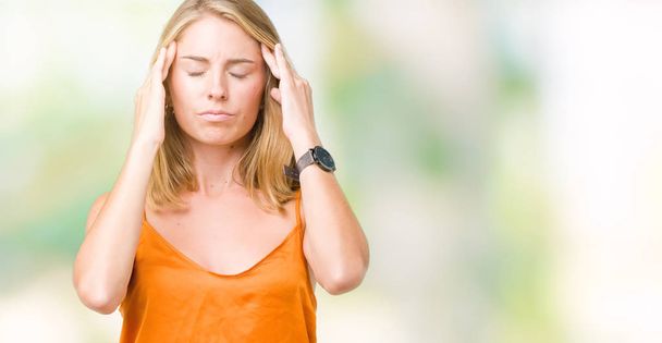 Mooie jonge vrouw die het dragen van oranje shirt over geïsoleerd achtergrond met hand op het hoofd voor pijn in hoofd, omdat stress. Lijden van migraine. - Foto, afbeelding
