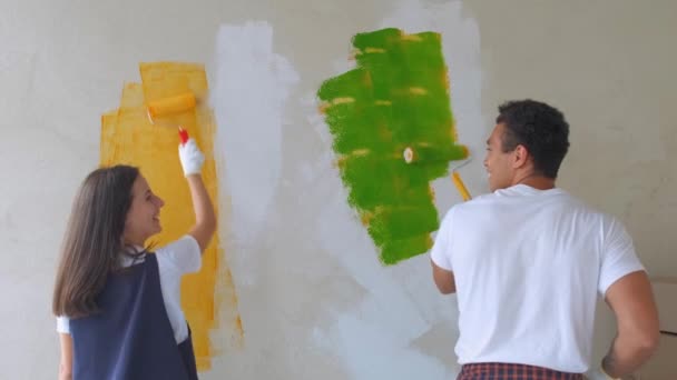 Home makeover and renovation: young happy couple painting their new house interiors using paint rollers - Footage, Video