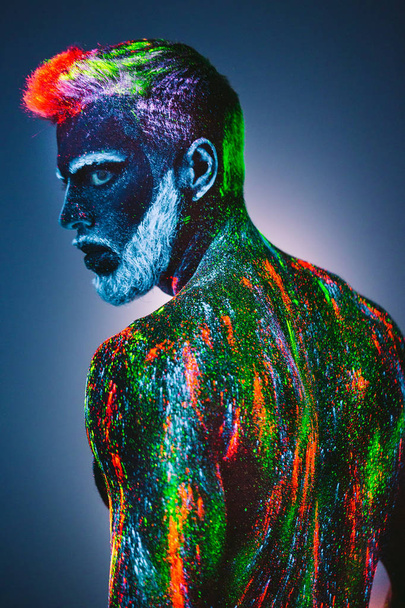 Concept. Portrait of a bearded man. The man is painted in ultraviolet powder. - Fotografie, Obrázek