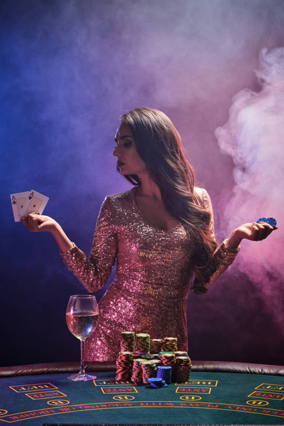 Brunette meisje met een perfecte kapsel en heldere make-up poseert met speelkaarten en chips in haar handen. Casino, poker. - Foto, afbeelding