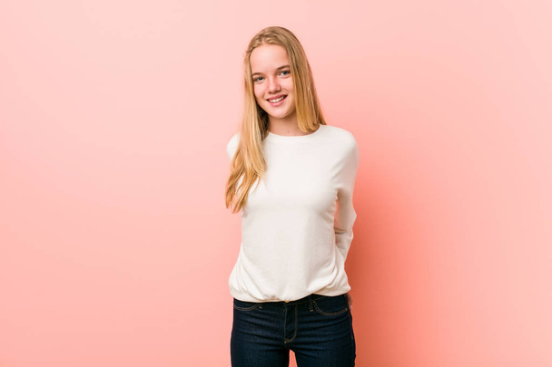 Caucasian teenager standing against a pink background - Foto, afbeelding