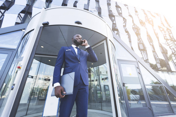 Афроамериканець бізнесмен розмовляв по телефону з сучасним офісними будівельними - Фото, зображення