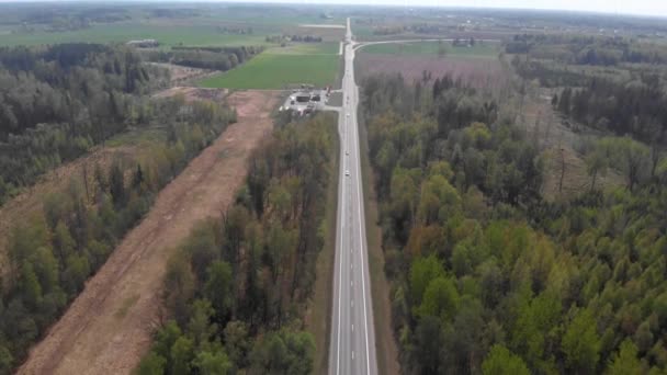 4k Luftaufnahme einer Straße mitten im Waldstreifen mit sich bewegender Trafik bei Tageslicht - Filmmaterial, Video