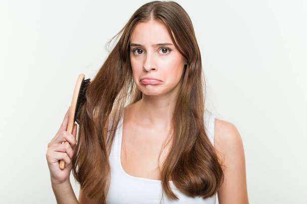 Молодая белая женщина расчесывает волосы
 - Фото, изображение