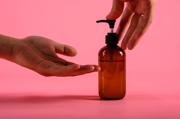 Man hands pushing pump plastic bottle isolated on pink background, clipping path. Mock up - Φωτογραφία, εικόνα