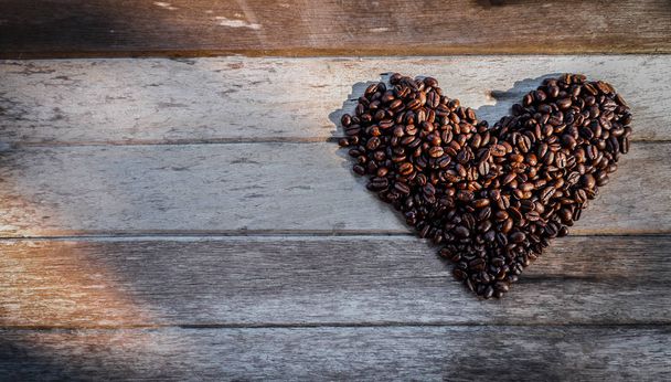Roasted coffee beans in the shape of heart on a wooden background - Foto, Imagem