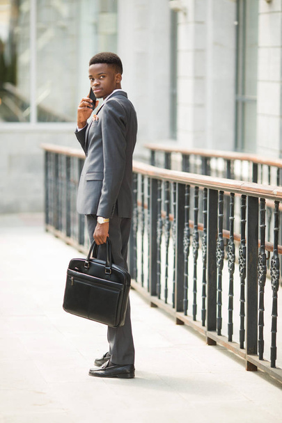 handsome young adult african man in suit and glasses talking on the phone - Photo, Image