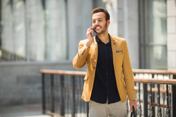 handsome young adult man in a suit talking on the phone with a hand gesture - Fotó, kép