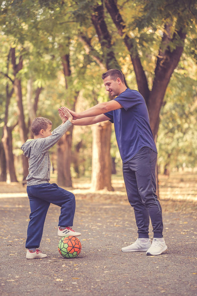 Ο πατέρας και ο γιος του παίζουν ποδόσφαιρο στο πάρκο, η ιδέα του Ente - Φωτογραφία, εικόνα