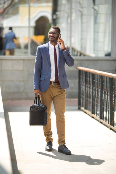 handsome young adult african man in suit and glasses talking on the phone - Fotoğraf, Görsel