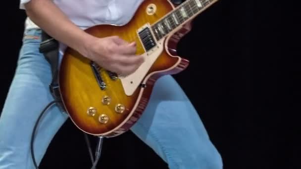 Młody zgrabny mężczyzna namiętnie grając kolorową gitarę elektryczną i bawić publiczność. - Materiał filmowy, wideo