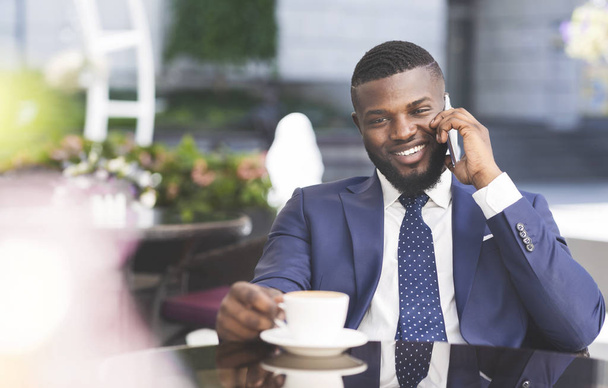 Αφρικανός Αμερικανός τύπος που μιλά στο τηλέφωνο σε υπαίθριο καφέ - Φωτογραφία, εικόνα