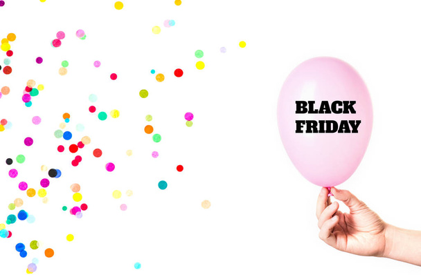 Black Friday inscription on pink balloon in hand with confetti isolated on white background. - Foto, Bild