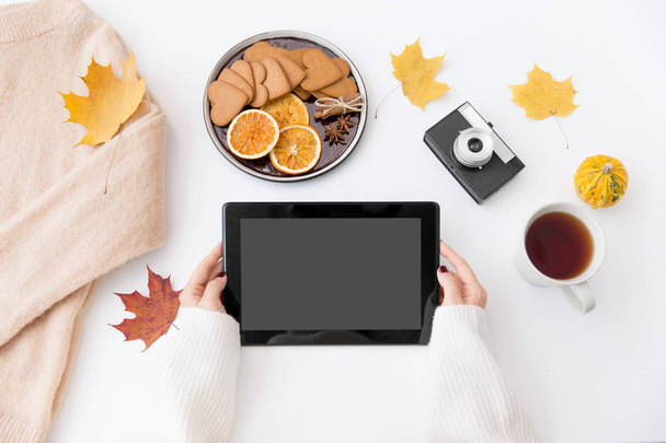 hands with tablet pc, tea and autumn leaves - Photo, image