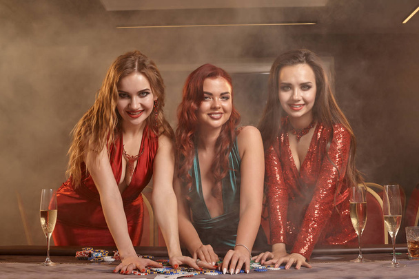 Drie mooie jonge vrouwen spelen poker in een casino. - Foto, afbeelding