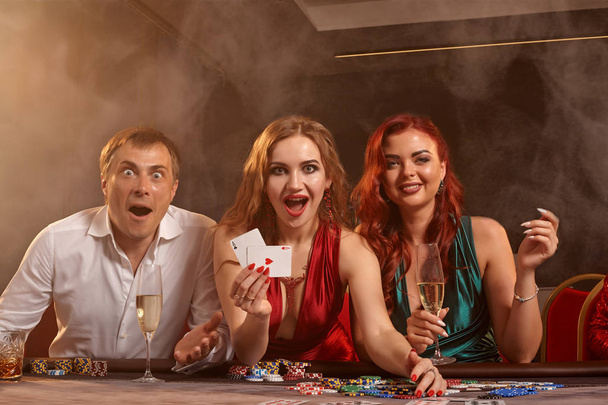 Grupa młodych zamożnych przyjaciół gra w pokera w kasynie. - Zdjęcie, obraz