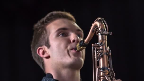 Atractive młody mężczyzna gra na saksofonie i bawić publiczność. - Materiał filmowy, wideo