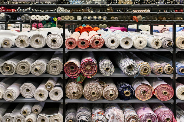 Fabric warehouse with many multicolored textile rolls - Fotoğraf, Görsel