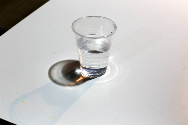 κρύο πόσιμο νερό χύνεται σε ένα πλαστικό Κύπελλο και φιάλη  - Φωτογραφία, εικόνα