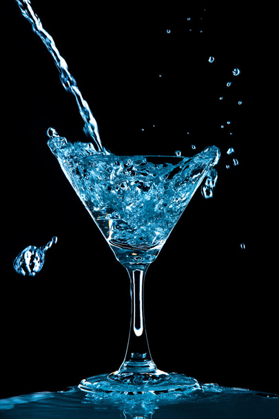 Vue du verre avec éclaboussure de curaçao bleu sur fond noir
 - Photo, image