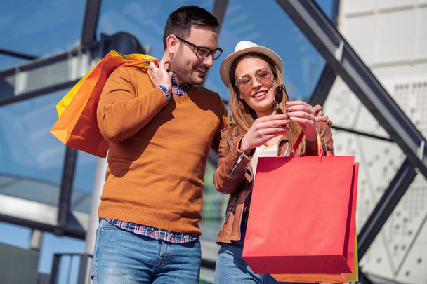Hermosa pareja amorosa joven llevando bolsas de compras y disfrutando juntos. - Foto, Imagen