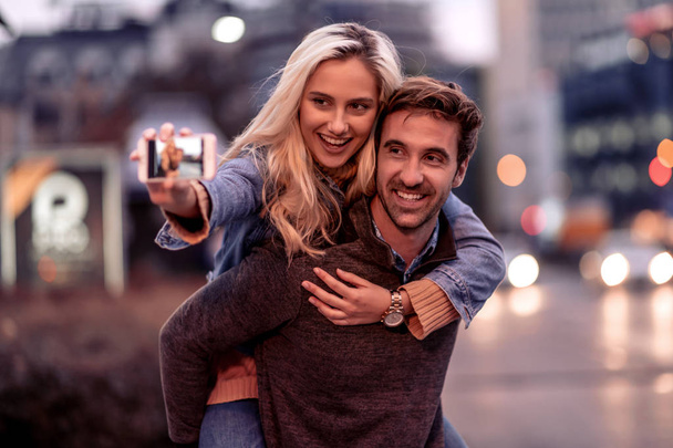Happy young couple taking selfie on city street. - Photo, Image