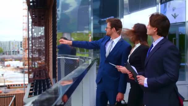 Confident businesspersons talking in front of modern office building. Businessmen and businesswoman have business conversation. Banking, professional job and financial market concept. - Footage, Video